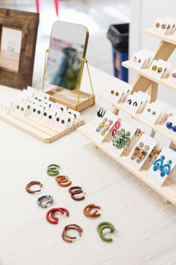 Variety of polymer clay earrings from Cositas PDX on a table