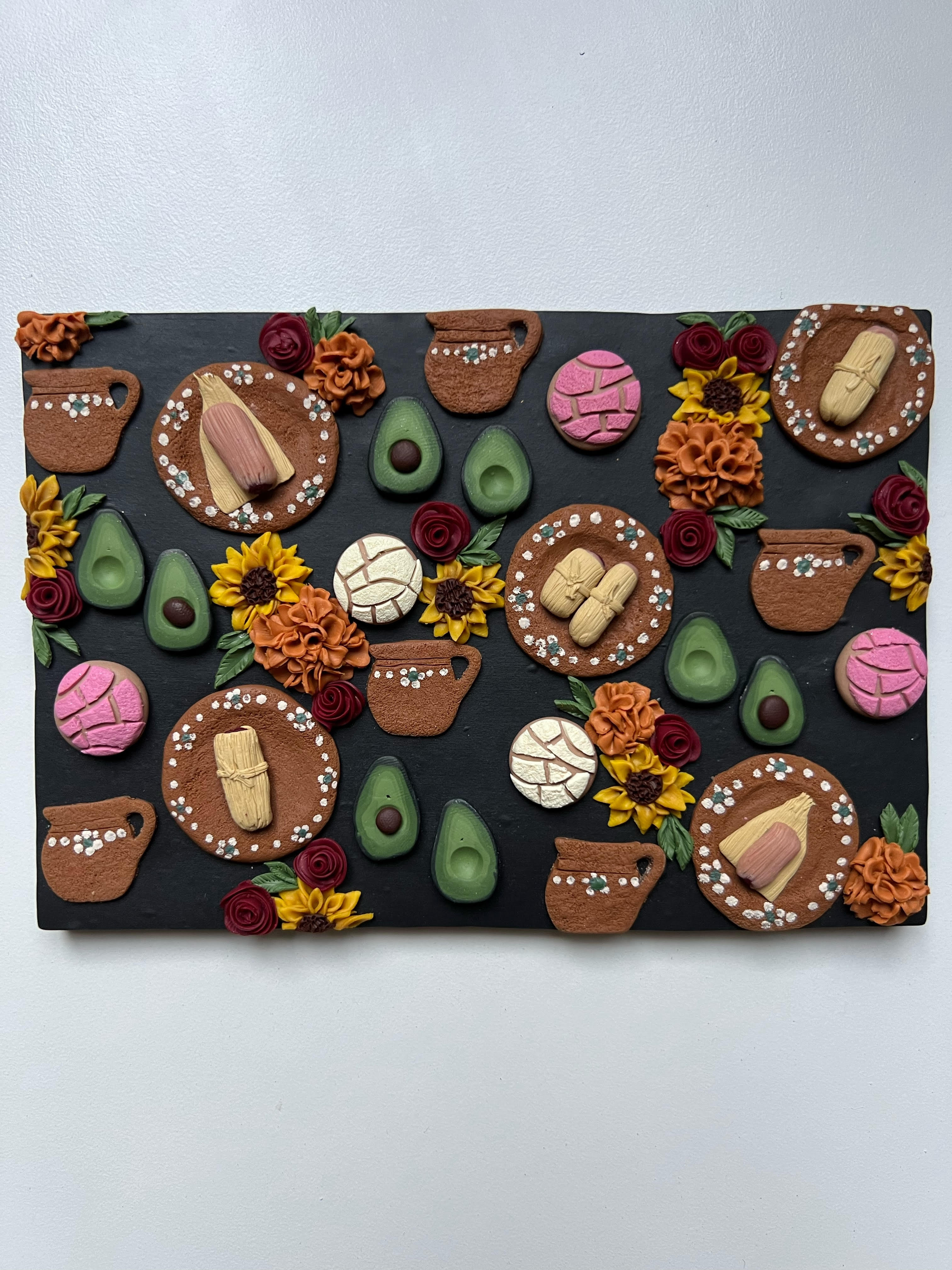 Polymer clay slab of tamales, avocados, flowers, and conchas
